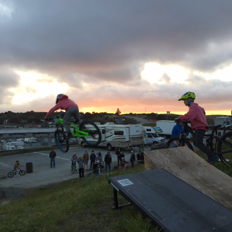 Kids jumping off a hill and into the sunset.